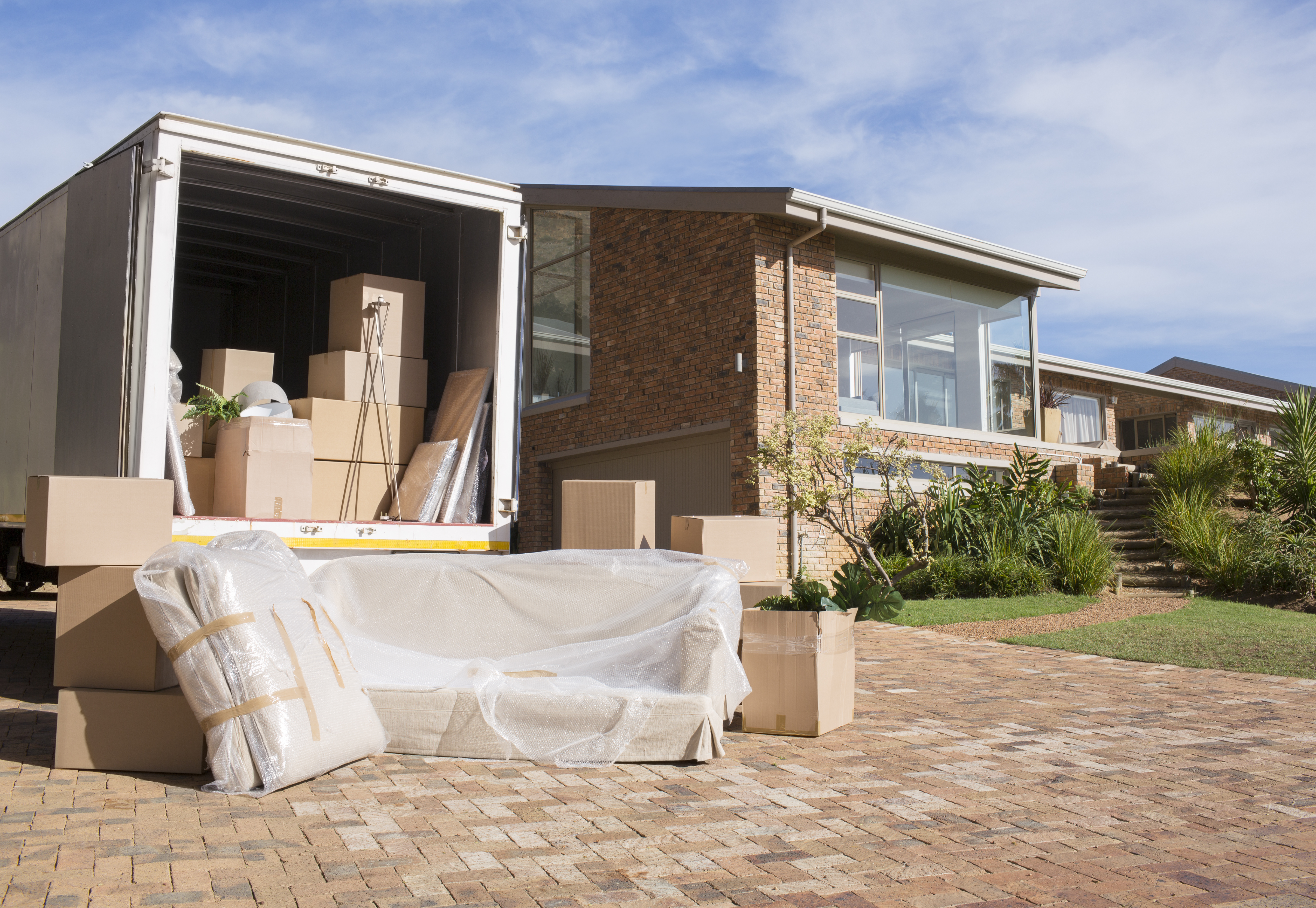 Moving truck unloading boxes and furniture outside brick residential home